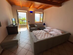 A bedroom with a bed, a desk, a chair, a lamp, and a view of the outdoors. - Casa Marie, a rustic natural stone home with a lake view and a rooftop terrace (Vercana)