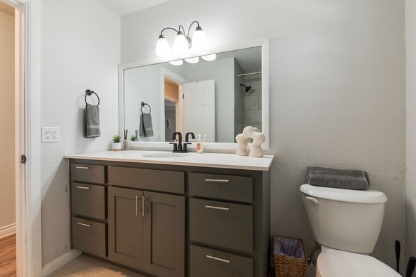 Een badkamer met een witte wasbak, donkere kastjes, een grote spiegel en een wit toilet.