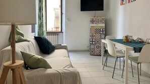 A living room with a sofa, a coffee table, a TV, and a patterned cabinet.