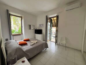 A modern hotel room with a bed, a TV, a small table, and a window with curtains. - Serene apartment with AC in charming Roma (Roma)