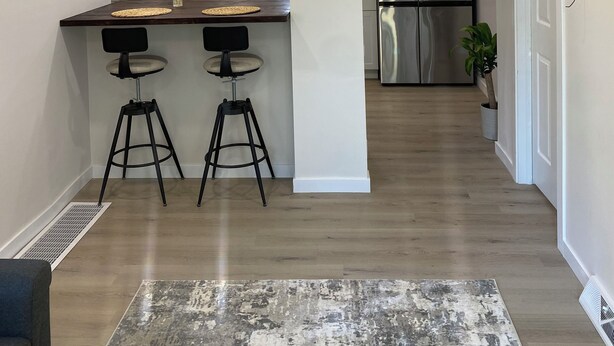A modern kitchen with white cabinets, a stainless steel refrigerator, and two bar stools. - Airport bungalow  (Coraopolis)