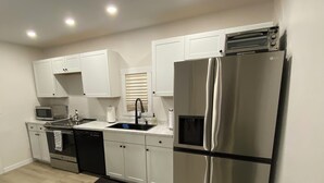 A modern kitchen with white cabinets, stainless steel appliances, and a black countertop. - Airport bungalow  (Coraopolis)