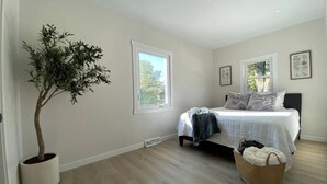 A bedroom with a bed, a potted plant, and a window. - Airport bungalow  (Coraopolis)