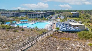 A resort with multiple swimming pools, a covered area with umbrellas, and a large building in the background.