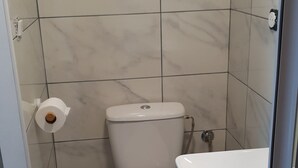 Une petite salle de bain comprenant des toilettes, un lavabo et un espace douche.
