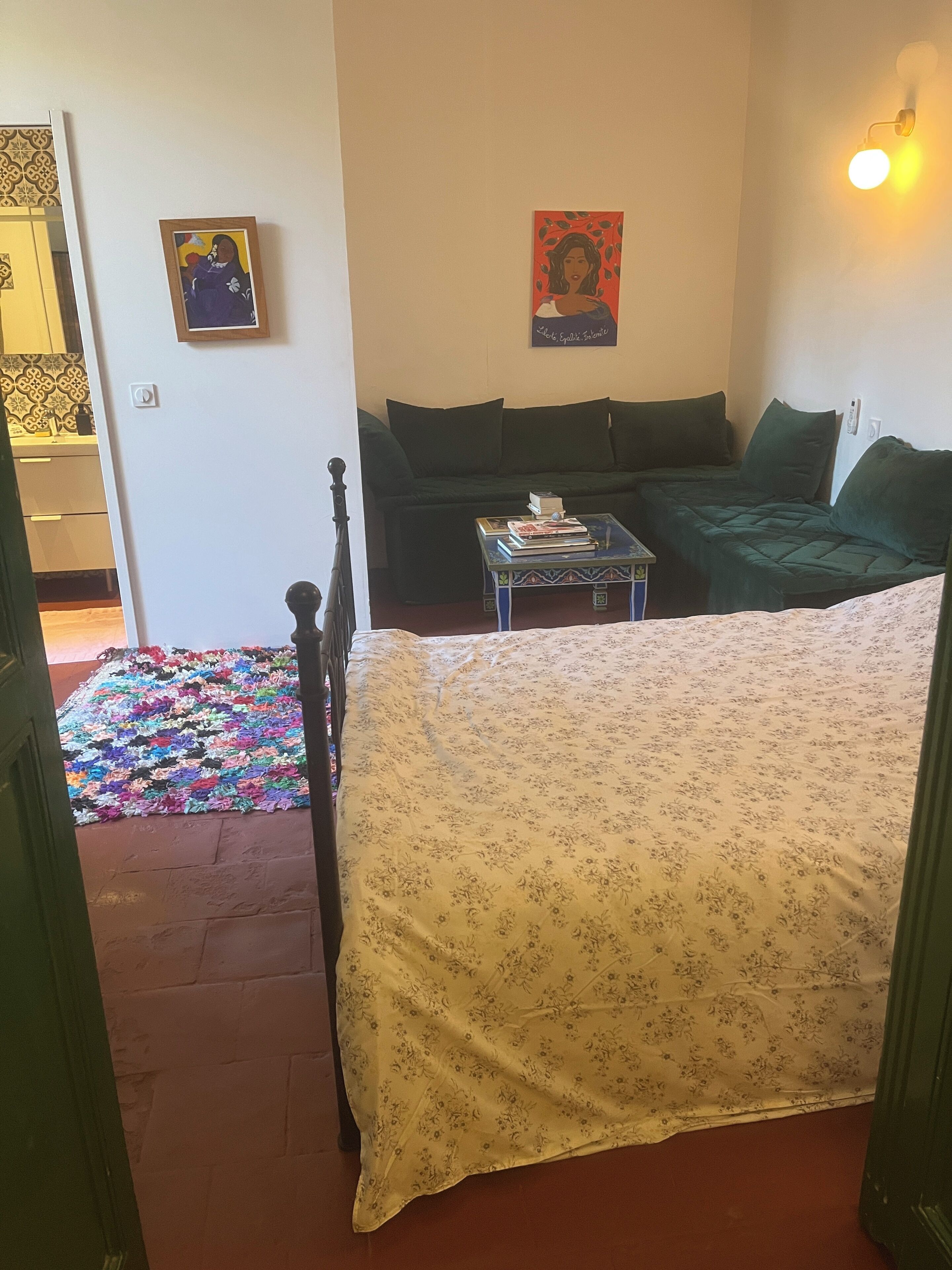 Una habitación con una cama, un sofá, una mesita y un tapete colorido.