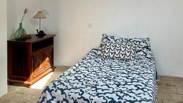 Un dormitorio con cama, mesita de noche, lámpara y aplique de pared.