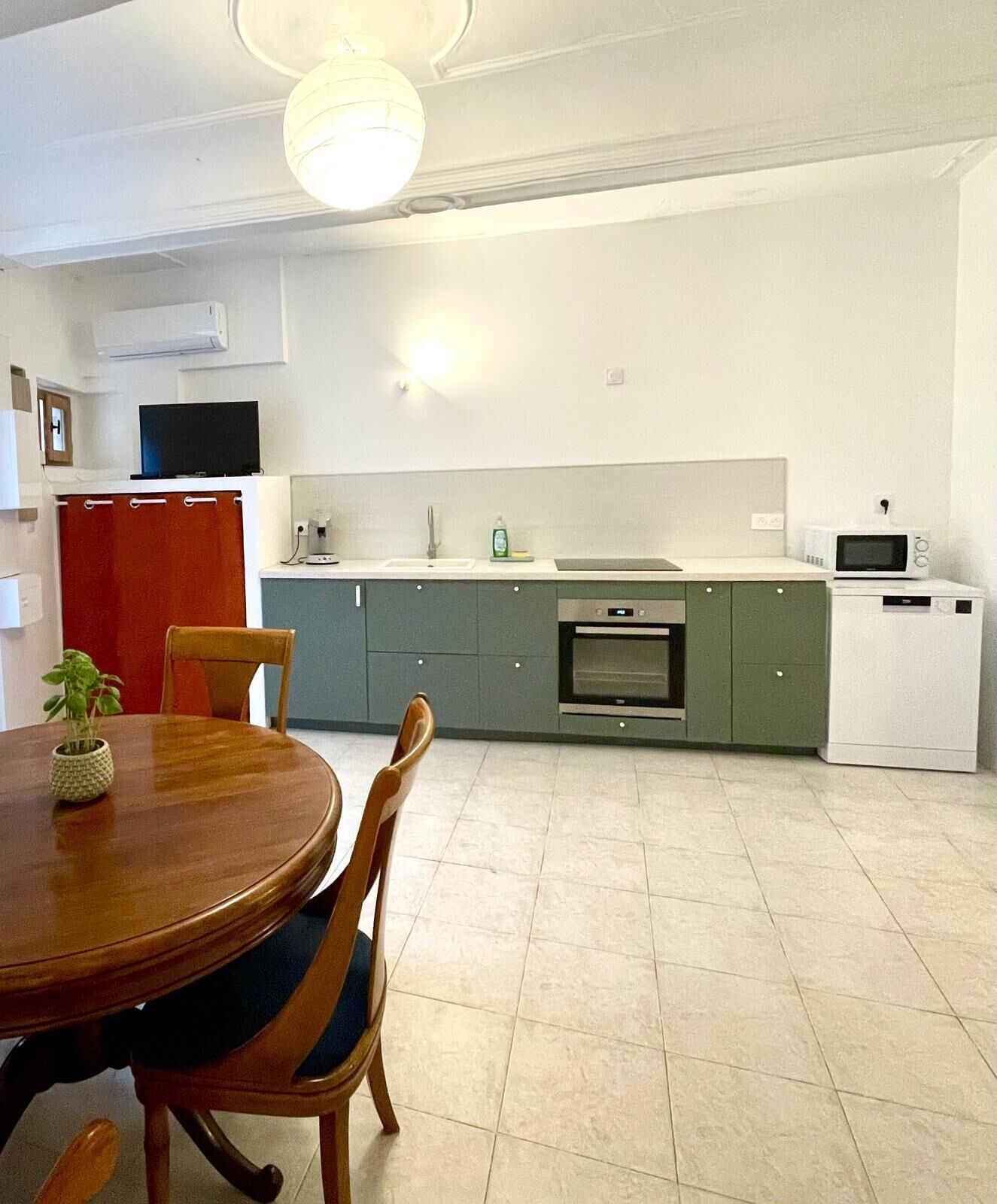 A modern kitchen with a dining table and chairs, a TV, and a microwave.