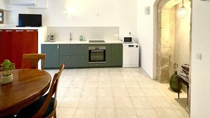 Cocina compacta con comedor, horno integrado, microondas y lavamanos.