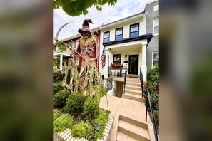 A residential building with a front porch, a staircase, and a garden area with a scarecrow decoration. - In the middle of Trendy NoMa/Union Market! Private Basement 1br/1ba Apartment (Washington)