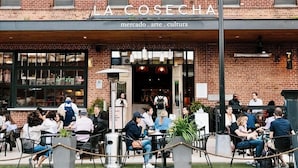An outdoor seating area of La Cosecha with brick walls and large windows.