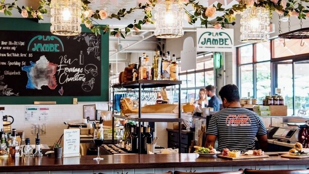 A bar area with a chalkboard menu, hanging flower garlands, and a bartender.