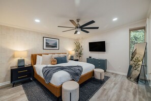 A modern bedroom with a bed, bedside tables, a ceiling fan, a TV, and a large mirror. - LakeFront with Pool! HotTub! Game Room! Sleeps 20+

 (Hot Springs)