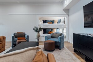 A modern living room with a sofa, armchairs, a coffee table, a TV, and a bunk bed with pillows. - LakeFront with Pool! HotTub! Game Room! Sleeps 20+

 (Hot Springs)