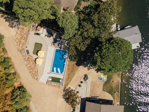 An aerial view of a property with a swimming pool, a covered patio area, and a dock extending into a body of water. - LakeFront with Pool! HotTub! Game Room! Sleeps 20+

 (Hot Springs)
