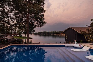 Piscina com vista para um lago e um edifício.