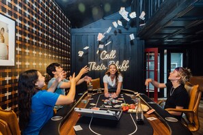 A group of people playing cards at a table with a neon sign that reads 'Call Their Bluff' in a room with patterned walls and a wooden ceiling. - LakeFront with Pool! HotTub! Game Room! Sleeps 20+

 (Hot Springs)