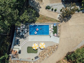 An aerial view of a swimming pool area with a deck, lounge chairs, and umbrellas. - LakeFront with Pool! HotTub! Game Room! Sleeps 20+

 (Hot Springs)