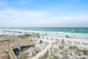 A beach with a wooden boardwalk, beach umbrellas, and a sandy shore. - Sea Destin - Private BeachFront Townhouse (Destin)