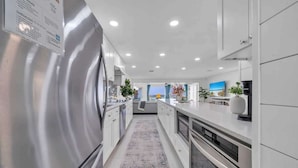 A modern kitchen with stainless steel appliances, white cabinetry, and a central island. - Sea Destin - Private BeachFront Townhouse (Destin)