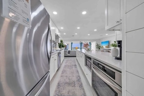 A modern kitchen with stainless steel appliances, white cabinetry, and a central island.