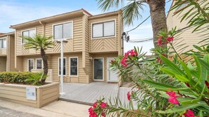 A two-story building with a flat roof, beige siding, and a small porch area. - Sea Destin - Private BeachFront Townhouse (Destin)