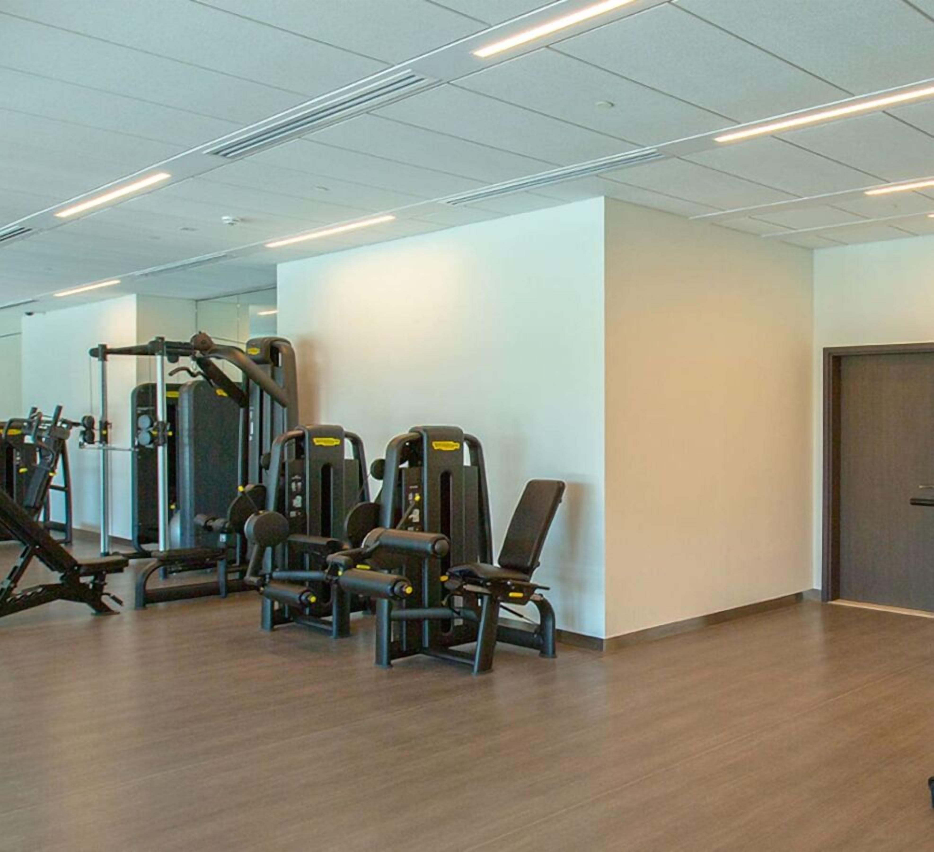 Een sportschool met trainingsapparaten, een spiegel en een deur.
