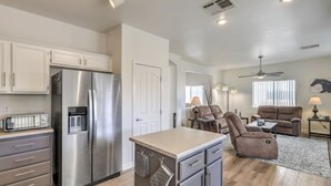 A modern kitchen with stainless steel appliances, a dining area with a sofa and armchairs, and a ceiling fan. - Starling Mesa | Extended Stay Modern Vegas (North Las Vegas)