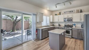 A modern kitchen with white cabinets, stainless steel appliances, and a large island. - Starling Mesa | Extended Stay Modern Vegas (North Las Vegas)