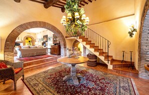 A spacious living area with a round wooden table, a staircase, and a dining table with decorative items.