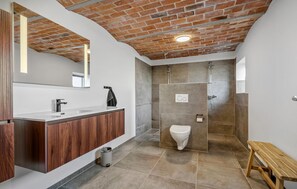 Une salle de bain moderne avec un meuble-lavabo en bois, une douche dotée d’une porte en verre et un banc.