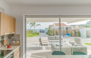 A modern kitchen with patterned tiles and wooden cabinets, leading to a patio with outdoor furniture and a view of a residential area. - 3 bedroom nice apartment in Donnalucata (Donnalucata)