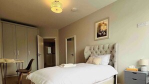 Un dormitorio con una cama grande, un escritorio y una silla.