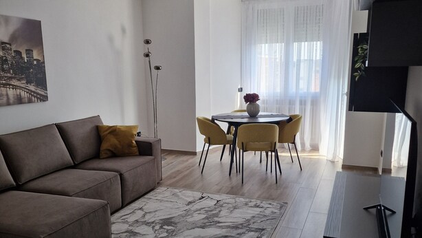 Ein modernes Wohnzimmer mit einer Couch, einem Couchtisch und einem Essbereich mit Stühlen.