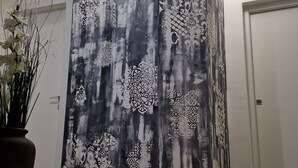 Ein Flur mit einem großen, abstrakten Gemälde an der Wand, einem Blumentopf und einer Tür rechts.