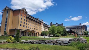 A multi-story hotel with a central courtyard, stone pathway, and surrounding greenery. - 5 BR Luxury Escape with Hot Tub, Home Theater, Arcade, Min from Lake & Slopes (Tafton)