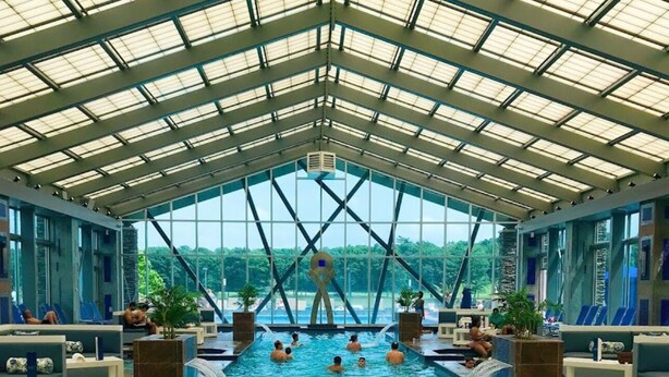An indoor swimming pool with a glass ceiling, multiple lanes, and lounge areas with seating. - 5 BR Luxury Escape with Hot Tub, Home Theater, Arcade, Min from Lake & Slopes (Tafton)