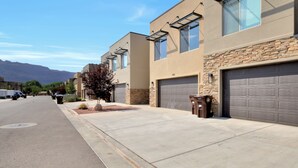 Une rue résidentielle moderne, bordée de maisons aux façades en pierre et dotées de portes de garage.