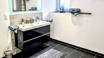 A modern bathroom with a large mirror, a sink, and a window.