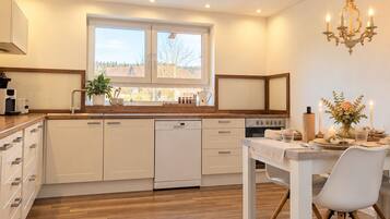 A modern kitchen with a central island, built-in appliances, and a dining area with a chandelier.