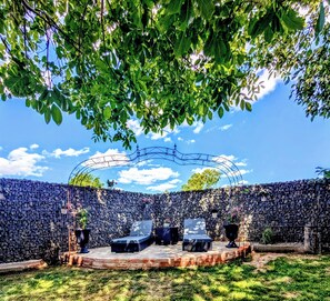 An outdoor seating area with a stone wall backdrop, a metal arch structure, and potted plants. - A small main resort in beautiful Franconia   (Obernbreit)