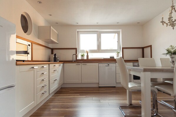 A modern kitchen with white cabinetry, a built-in oven, and a window above the sink.