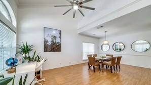 A spacious dining area with a wooden floor, a ceiling fan, and a dining table with chairs.