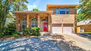A two-story house with a red front door, a garage, and a covered porch.