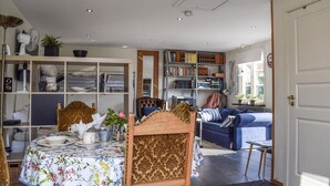 A cozy living room with a dining area, a bookshelf filled with books, and a blue sofa.