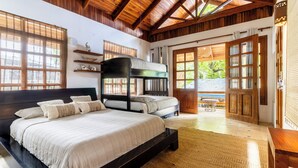 Une chambre avec un grand lit, un lit superposé, des poutres en bois et une vue sur l’extérieur.