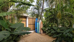 Un jardin tropical avec une clôture en bois et trois planches de surf appuyées contre celle-ci.