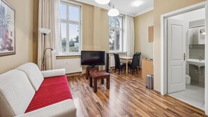 A modern living room with a sofa, TV, dining area, and kitchen. - Gorgeous apartment in Anklam (Anklam)