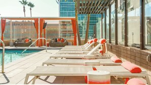 Un espace aménagé au bord de la piscine, avec des chaises longues, une piscine et une vue sur un bâtiment moderne.