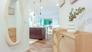 Une cuisine moderne avec des meubles de couleur sombre, un plan de travail en bois et un grand miroir.